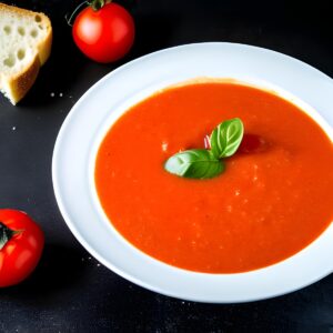 Homemade tomato soup on a dark background with crispy bread