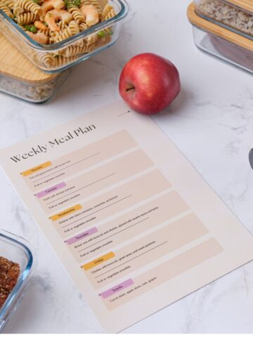 Meal plan on marble kitchen bench with glass containers full of meal prepped food