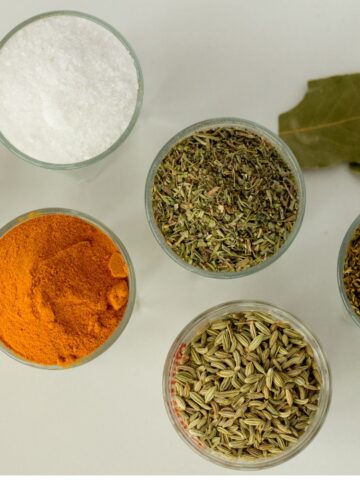 Multiple bowls of spices on a white background