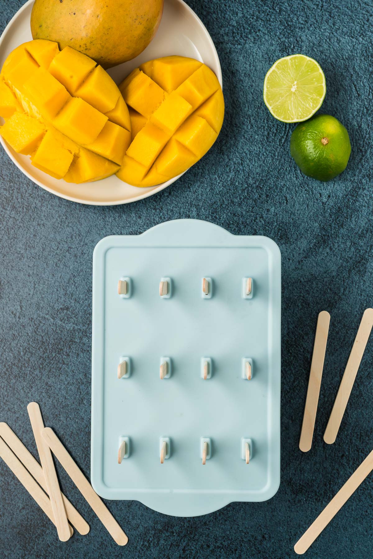popsicle mold with cut up mango and lime around it