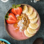 Strawberry banana smoothie bowl with cut banana, strawberries, granola and coconut