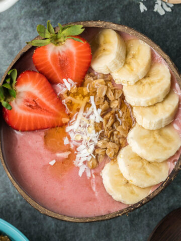 Strawberry banana smoothie bowl with cut banana, strawberries, granola and coconut