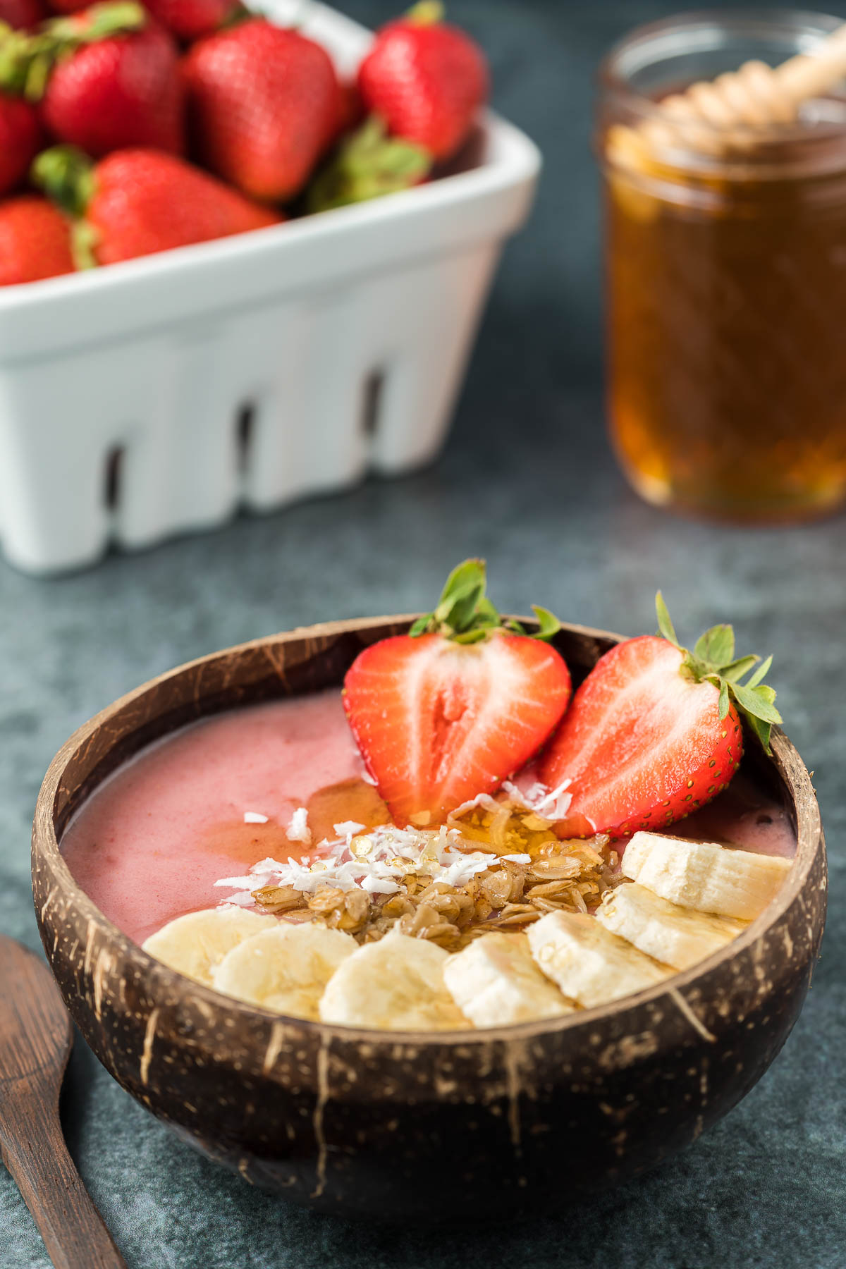 Strawberry banana smoothie bowl with jar of honey and punnet of strawberries