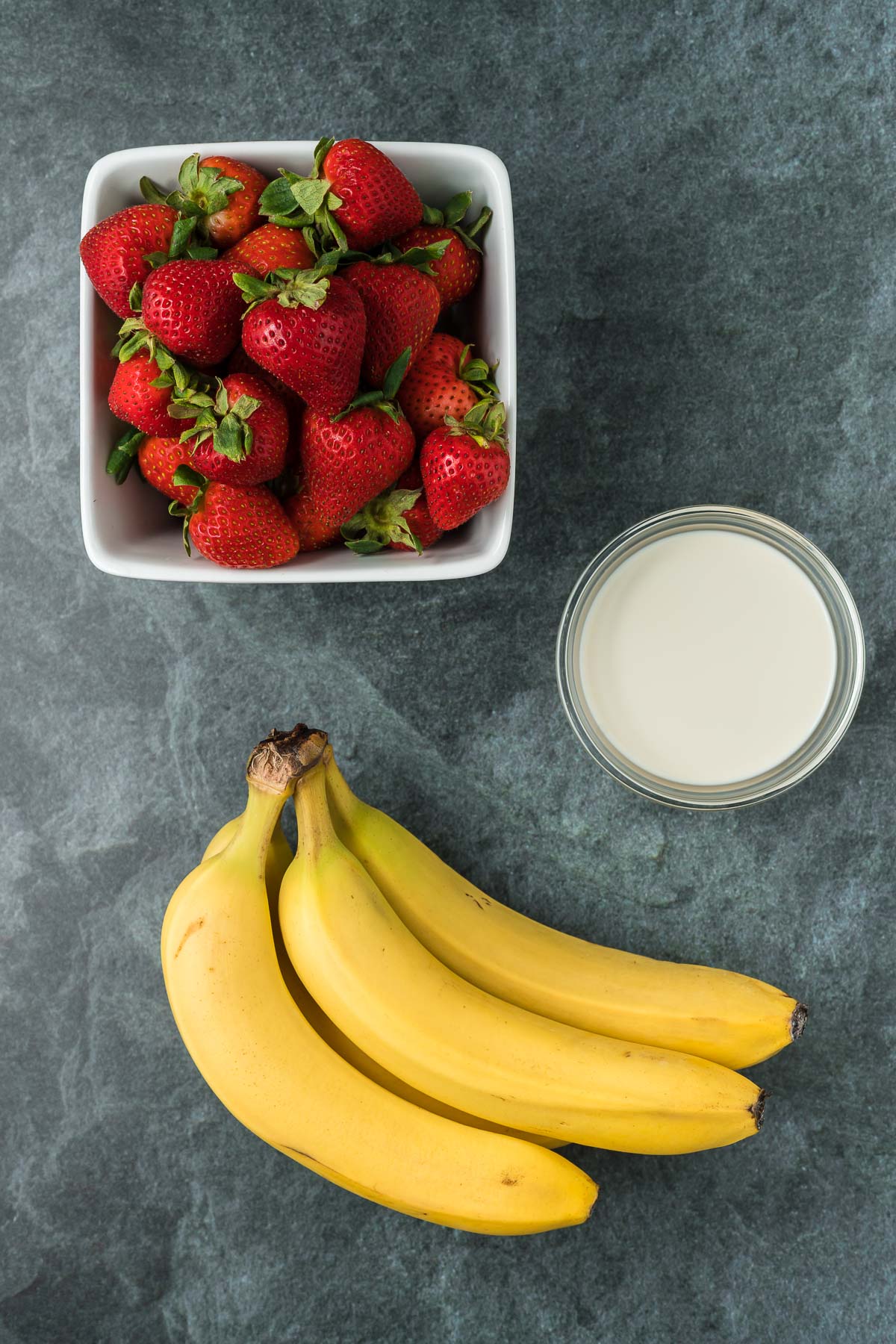 Punnett of strawberries, 3 bananas and oat milk on a dark background